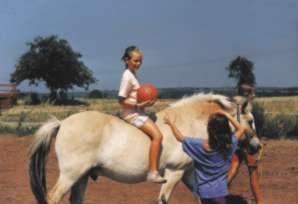 Ute und Kind auf einem Pferd machen Ballübung